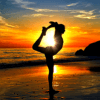 Silhouette of a woman doing yoga on a beach at sunset.